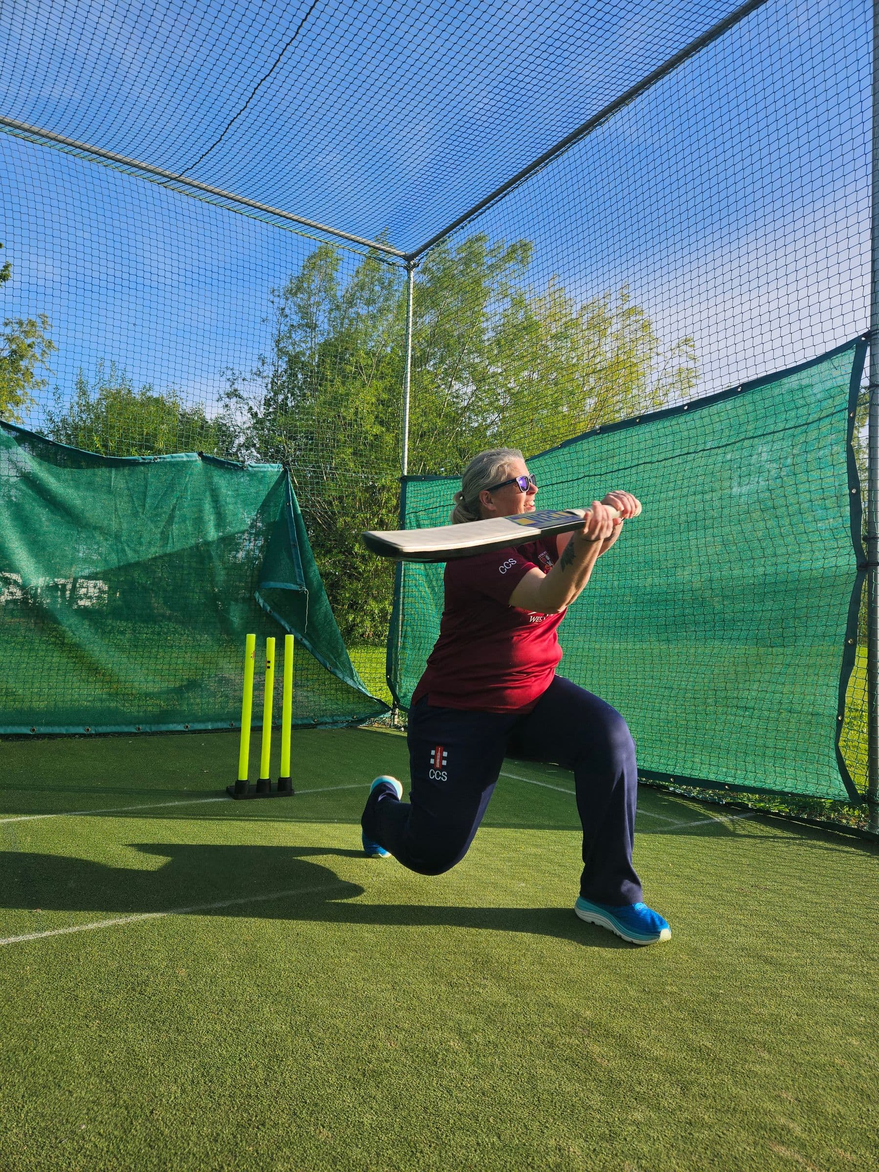 A Tewkesbury player sweeping in the outdoor nets on a sunny evening