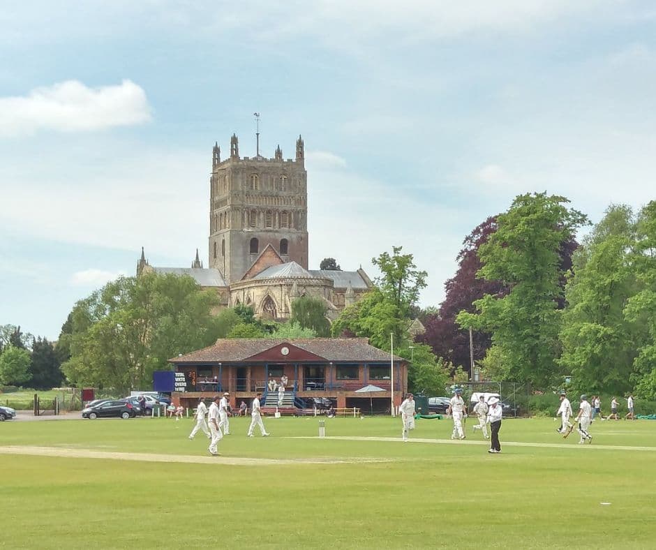 A match in progress at the Tewkesbury ground, with the pavilion and Tewkesbury Abbey behind